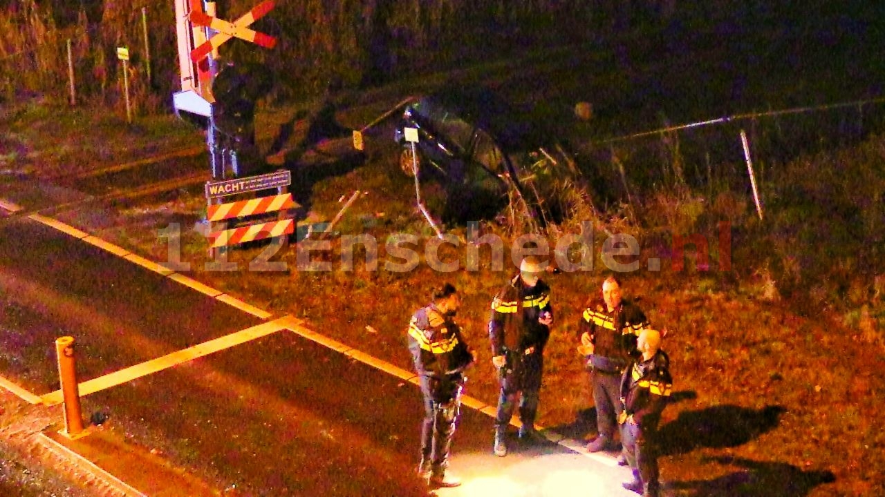 VIDEO: Auto ramt spoorwegovergang in Enschede en komt op spoor terecht, bestuurder spoorloos